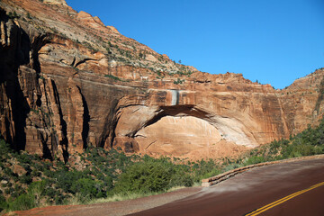 The arch shaped red mountain with the red paved road of Zion National Park