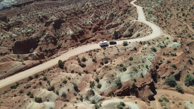 Aerial view pulling camping trailer down desert road. Black suv towing small travel trailer.
