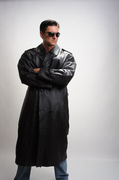 The sexy sniper poses for the photo wearing a trench coat. 