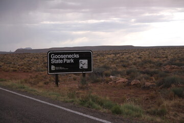 Goosenecks State Park brown sign on a road during a cloudy day