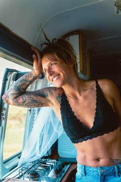 Smiling woman in bra looking at window in camper van