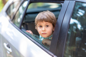 little boy with head leaned through the open window of a car