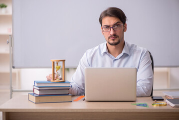 Young male teacher in time management concept