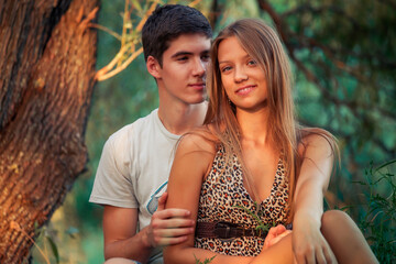 Obraz premium Beautiful young couple in the park sitting hugging on the grass