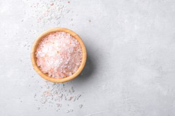 pink himalayan salt in a wooden bowl with scattered salt on a light grey background, copy space, top view, flat lay - obrazy, fototapety, plakaty