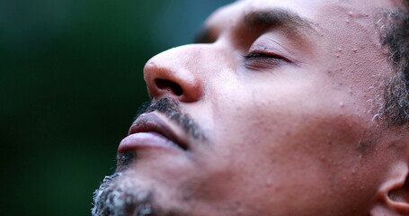 African american man face closing eyes feeling spiritual contemplating and celebrating life. Black person opening eyes to sky