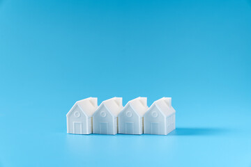 Miniature 3D printed model house on blue background for home or real estate market
