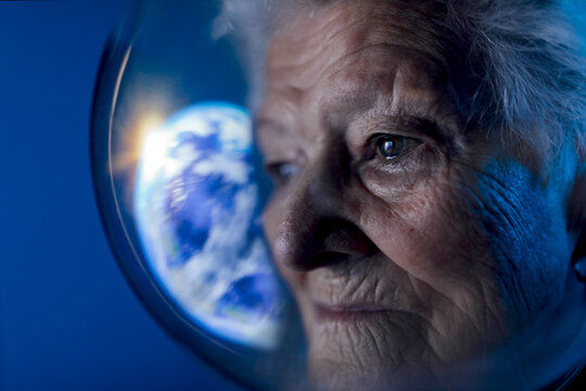 Senior woman in spacesuit looking at Earth