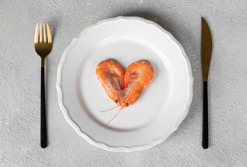 Two boiled shrimp in the shape of a heart on a round white plate on a light background, a concept for Valentine's Day