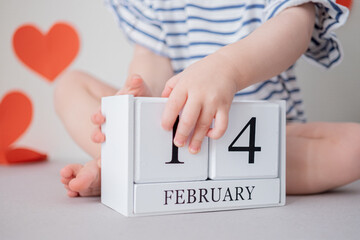 Toddler's hands close up with 14 February date calendar. Saint Valentine's celebration concept....