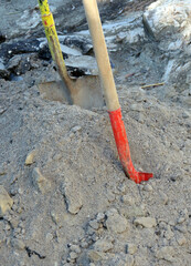 Pile of dirt, rocks, asphalt, sand with two shovels at a street repair digging site