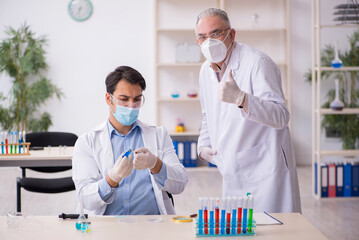 Two male chemists working at the lab during pandemic