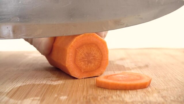 The cook cuts carrots on a cutting board.