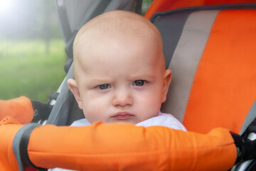 Little boy with serious face in stroller. 