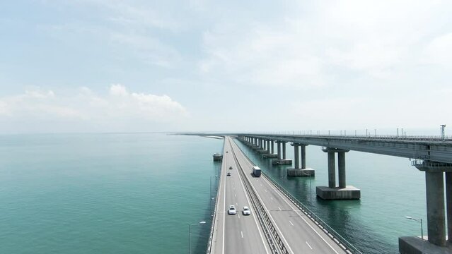 Summer view from a helicopter. Action. A huge bridge for moving cars made high above the sea and the blue daytime sky.