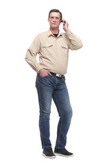 Serious young casual man standing with a hand in his pocket and speaking on the phone