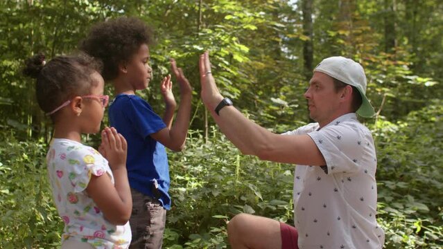 Father teaches children playing with hands. Patty Cake game is easiest hand-clapping games to start. Lifestyle, outdoor. 