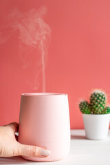 Woman's hand turns on humidifier or aroma lamp. Steam from a humidifier close-up. The concept healthy lifestyle, and comfortable living conditions