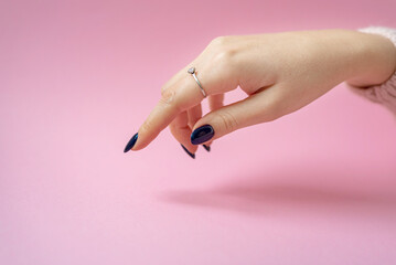 female hand with a beautiful blue manicure on a pink background. gel polish coating. ring on hand.place for text.
