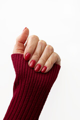 well-groomed female hand with a red manicure and a red sweater on a white background. isolate. place for text