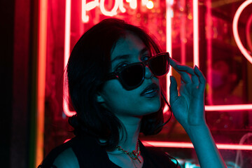 Sillhoutte of hip-hop girl in cap at the neon light. Fashion portrait of modern young woman in cap and sunglasses. - obrazy, fototapety, plakaty