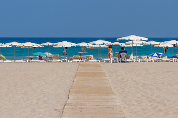 Naklejka premium beach shore with sunbathers under white umbrellas