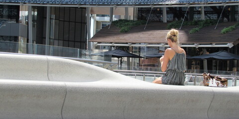 Giovane ragazza bionda seduta su un muretto in piazza - relax