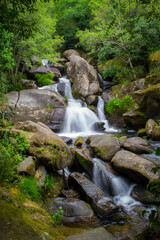 Fototapeta premium There is no better place to find yourself than to sit by a waterfall and listen to its music.No hay mejor lugar para encontrarse con uno mismo que sentarse junto a una cascada y escuchar su música.