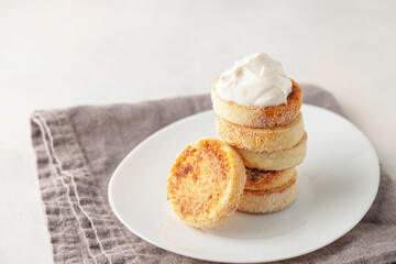 Cottage cheese Syrniki with sour cream in a plate on the table. Traditional Russian food