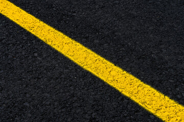 Fototapeta premium Yellow line on fresh asphalt to mark road works or temporary obstruction. 