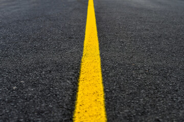 Yellow line on fresh asphalt to mark road works or temporary obstruction. 