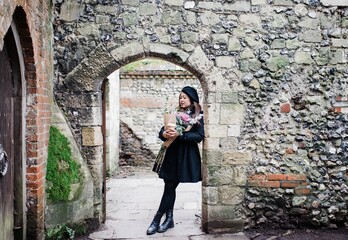 Asian woman leaning against castle ruins in UK