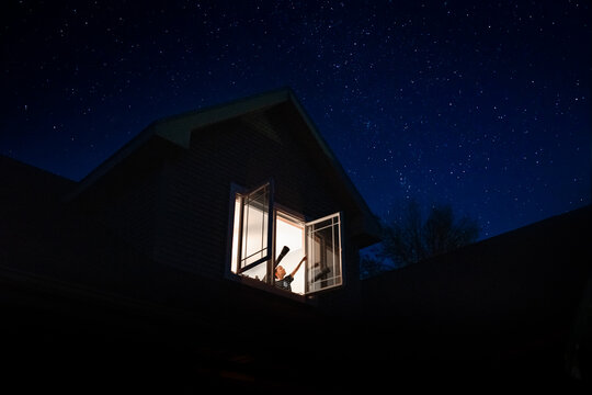 a child pointing to the stars from his bedroom window
