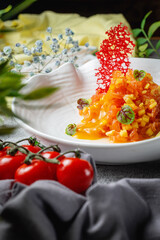 Mango and salmon salad with gravy and mashed avocado and lime in a plate on a gray stone table. Restaurant Menu