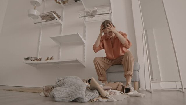 Low-angle slowmo shot of upset young woman throwing her clothes on floor having nothing to wear