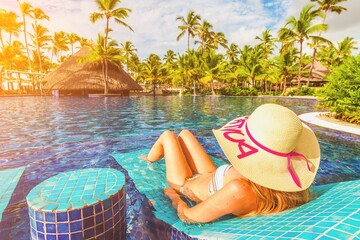 Luxury travel end resort hotel tourist lady tanning in bikini by the swimming pool