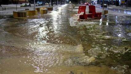 Water supply accident in the city. Water flows over the paving slabs in the winter time in the evening.