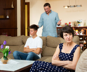 Parents swear among themselves. Offended son sits on a sofa. High quality photo