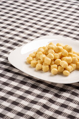 Potato gnocchi without sauce on a white plate on a black and white checkered tablecloth, selective focus.