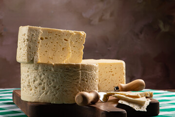 Semi-cured cheese from Brazil arranged on a rustic board on a green and white checkered tablecloth, selective focus.