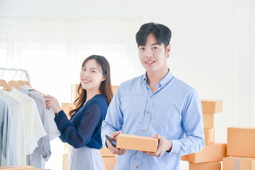 Startup small business man working with box and his female co-worker smiling on background.