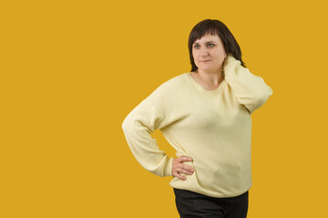 woman stands and straightens her hair on a yellow background