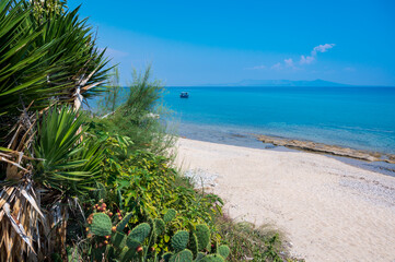 Traumhafter Strand mit Kakteen und Boot im Hintergrund in der nähe vom Turm von Apollonia - Paralia Folias, Pirgos Apollonias, Griechenland 