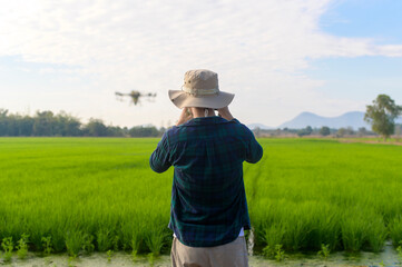 Young smart farmer controlling drone spraying fertilizer and pesticide over farmland,High technology innovations and smart farming