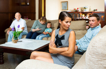 Young frustrated woman sitting separately having problems in relationship with her large family