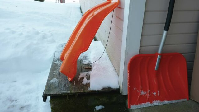 An orange snow plower on the side of the house during the winter season in Estonia