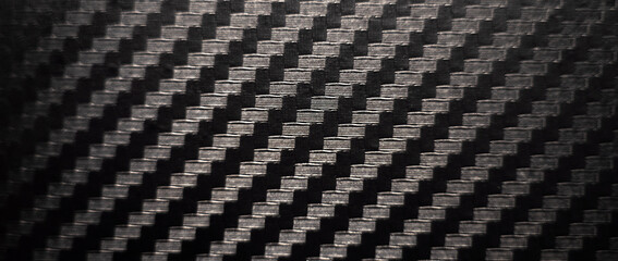 Photo of the texture of black carbon fiber. Carbon dark background of rectangular shape. Black sports film for pasting cars.