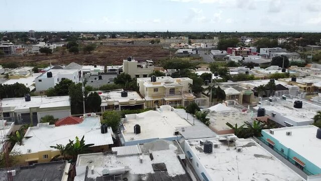 Rep&uacute;blica Dominicana, Bani 2022 - dron volando en reversa capturando nuevos edificios residenciales con vista a un paisaje rural en crecimiento.