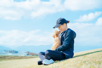 スポーツウェアで犬の散歩をする女性（抱く）
