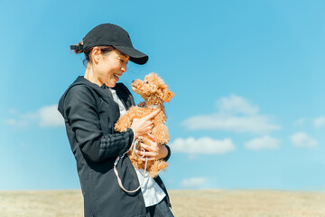 スポーツウェアで犬の散歩をする女性（抱く）

